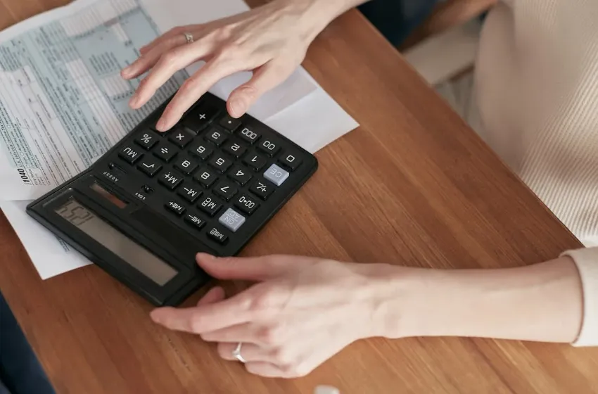 5 Proven Ways to Slash Home Energy Bills Person with calculator calculating bills.